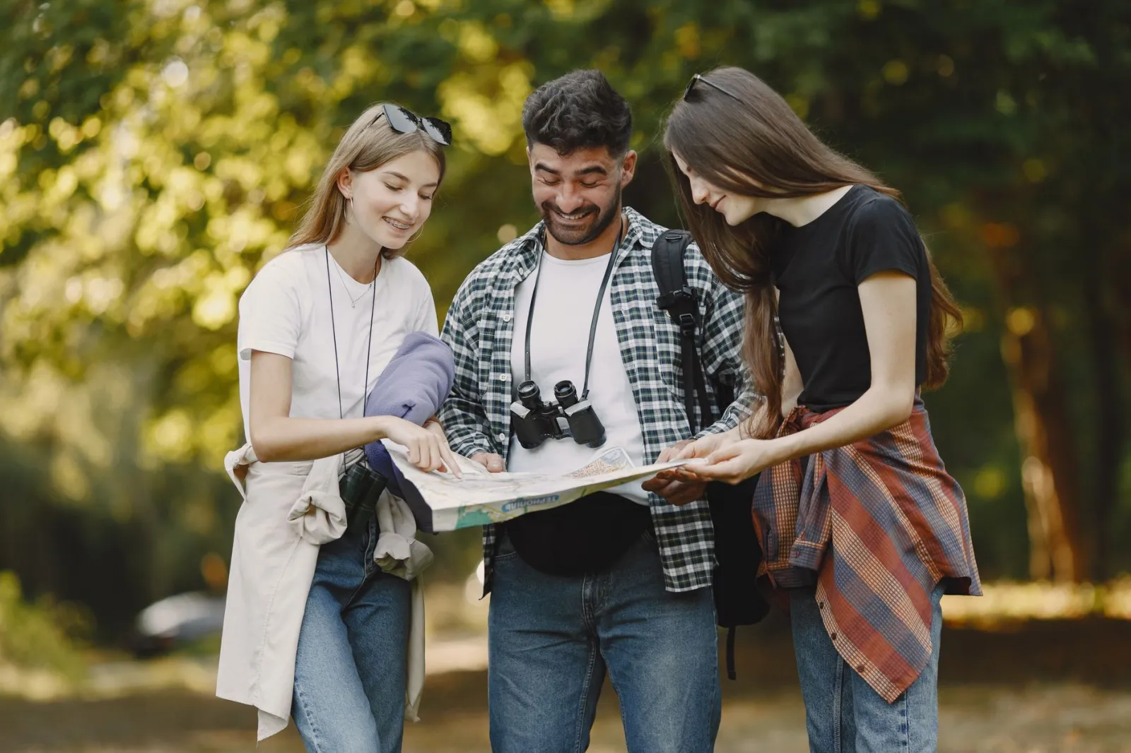 A group of friends joyfully navigates the outdoors with a map, embodying adventure and exploration.
