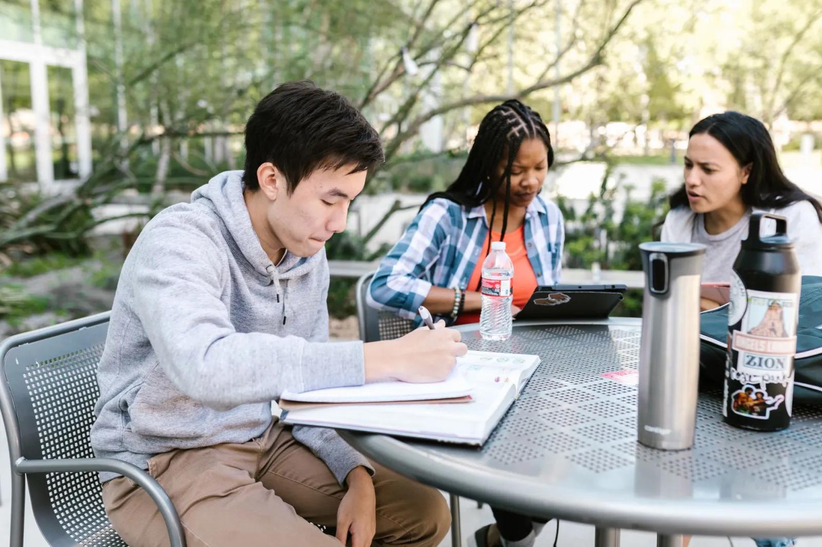 A diverse group of students collaborating and studying together outdoors at a college campus.