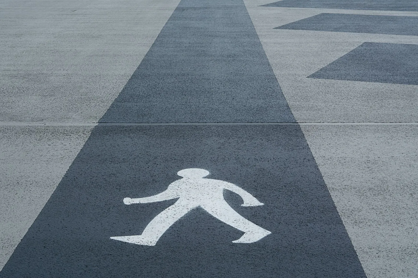 Close-up of a marked pedestrian crossing symbol on a concrete pathway.
